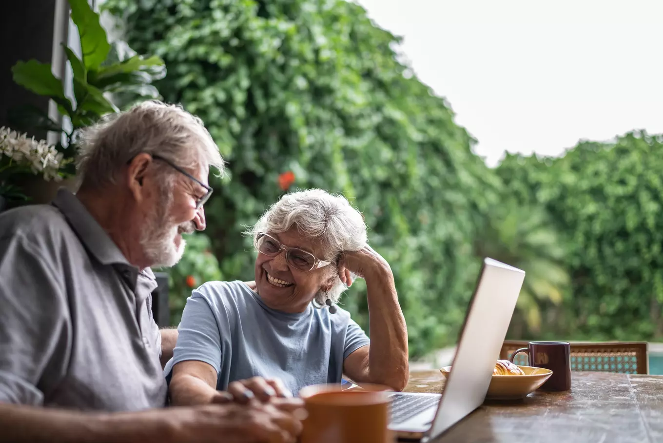 An older couple looking at a computer and smiling 